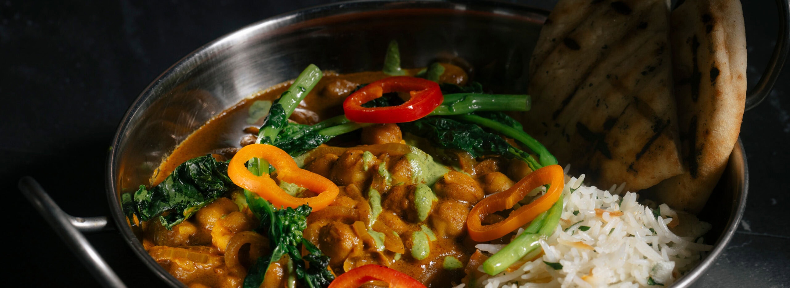 Brightly colored bowl of soup with beans ricke, and broccoli.