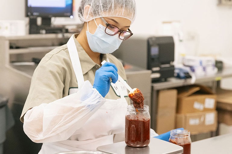 a woodland gourmet employee weighing a jar of spices