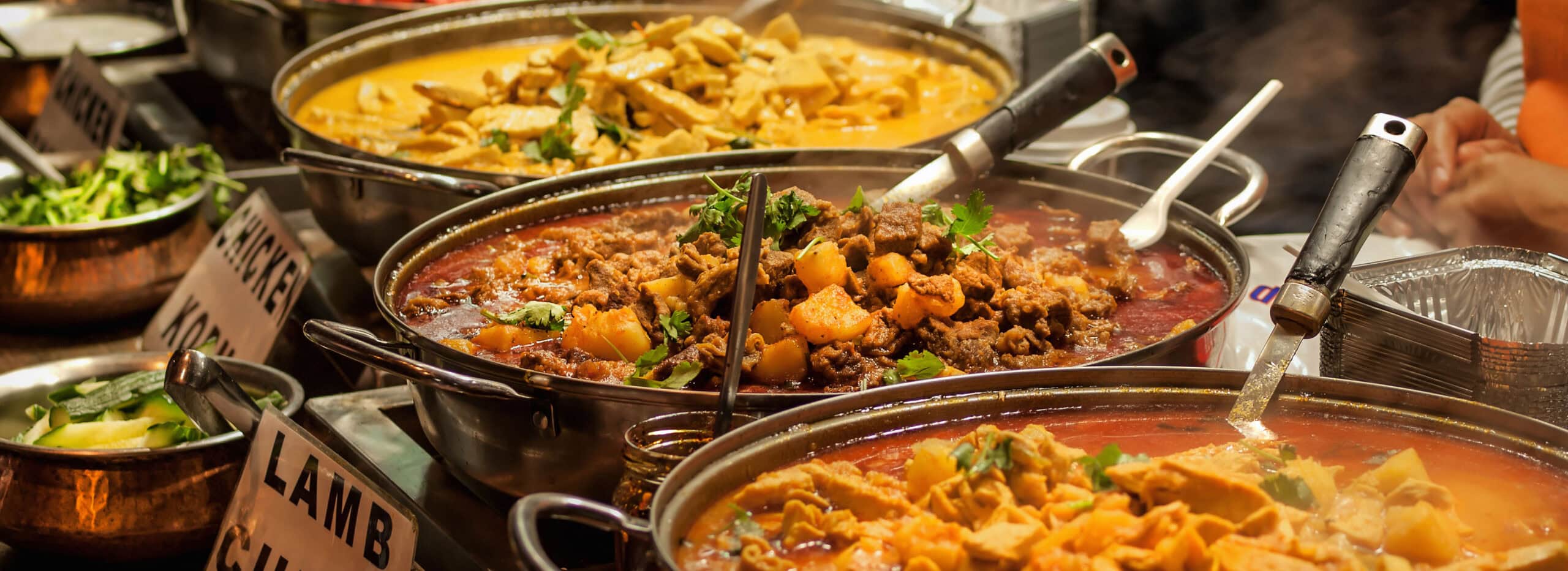 3 pans holding a variety of stewed meats and vegetables