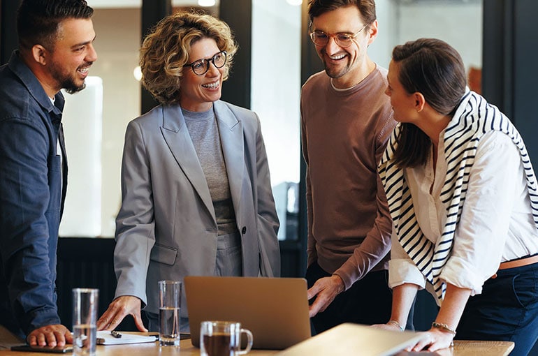 A group of people collaborating in front of a laptop