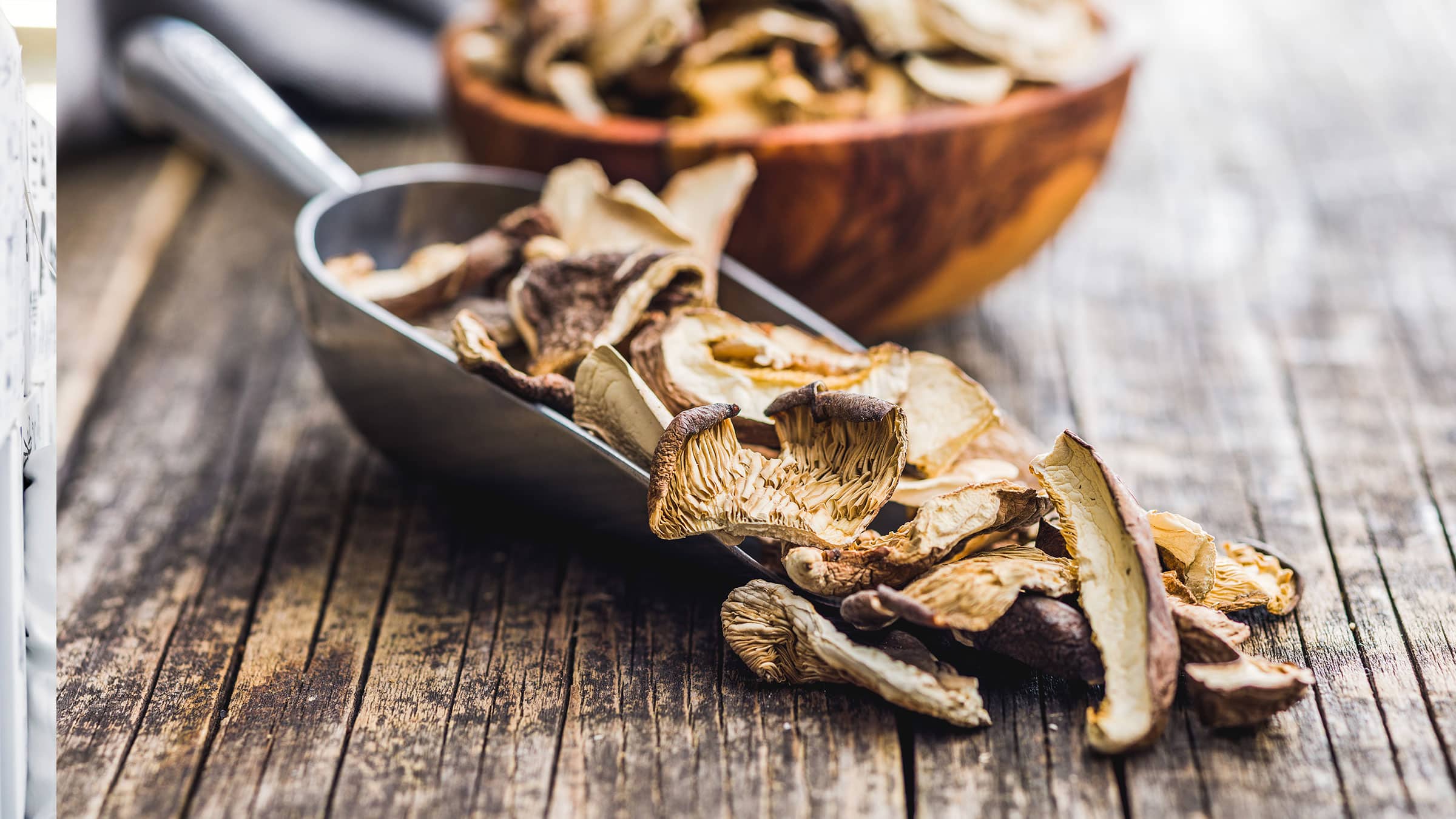 a scooper and a wooden bowl with dried mushrooms