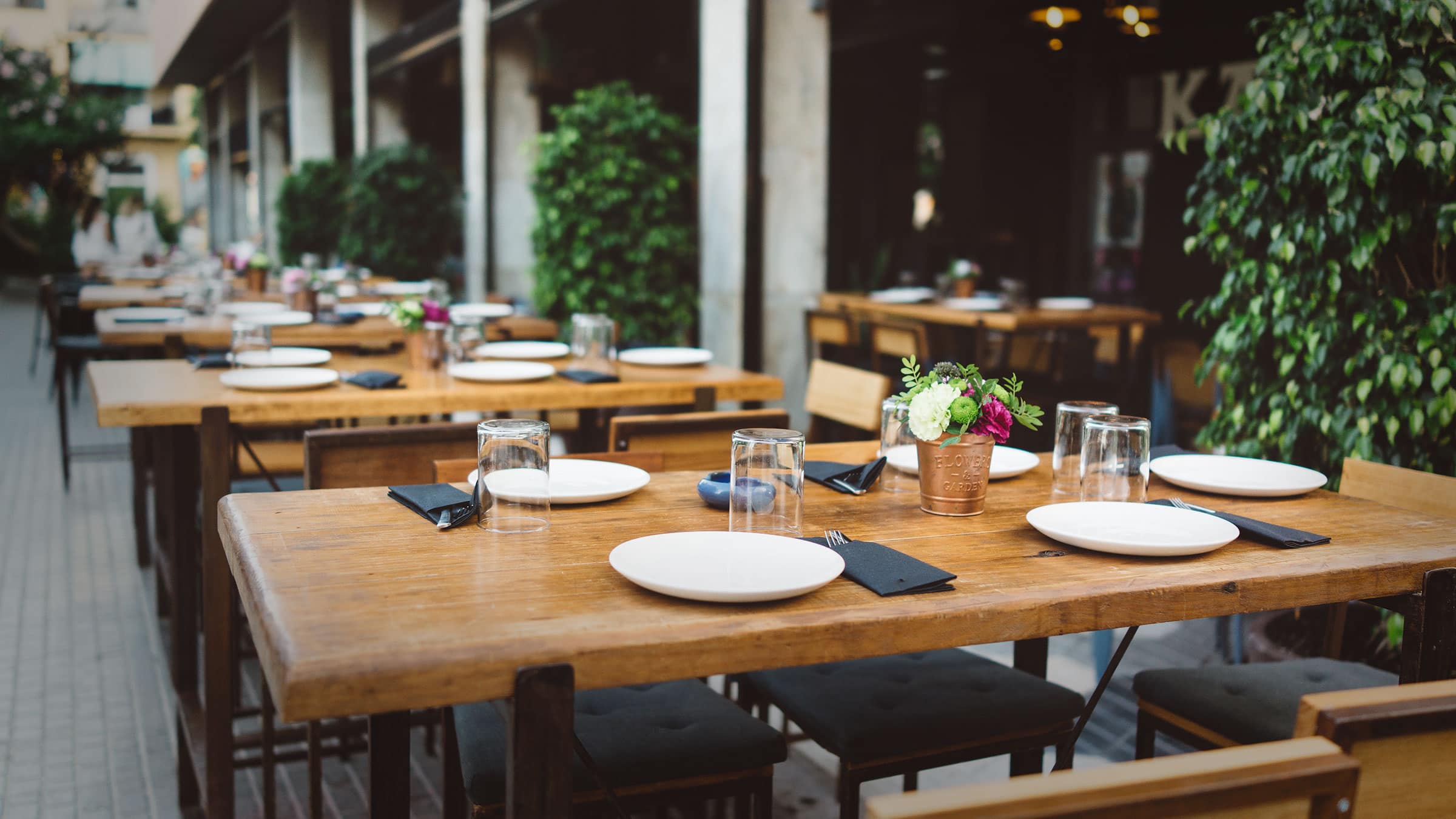 Foodservice tables and chairs showing tables set with dishes and centerpieces ready for guests.