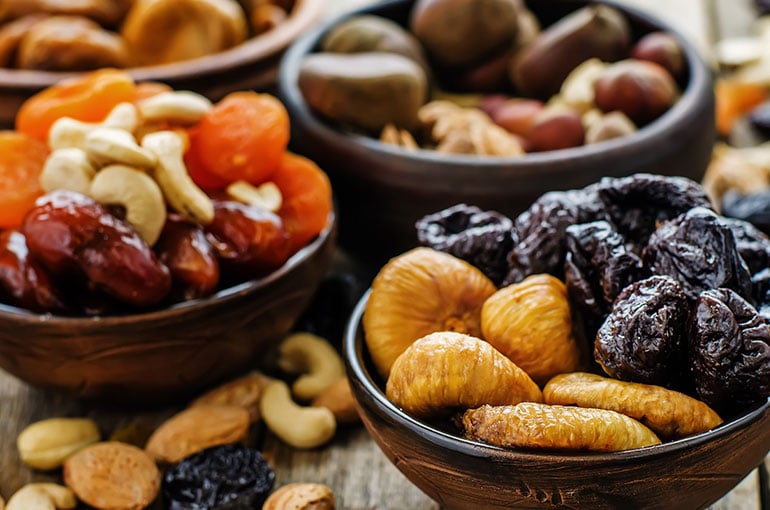 3 wooden bowls of mixed nuts, and fruits