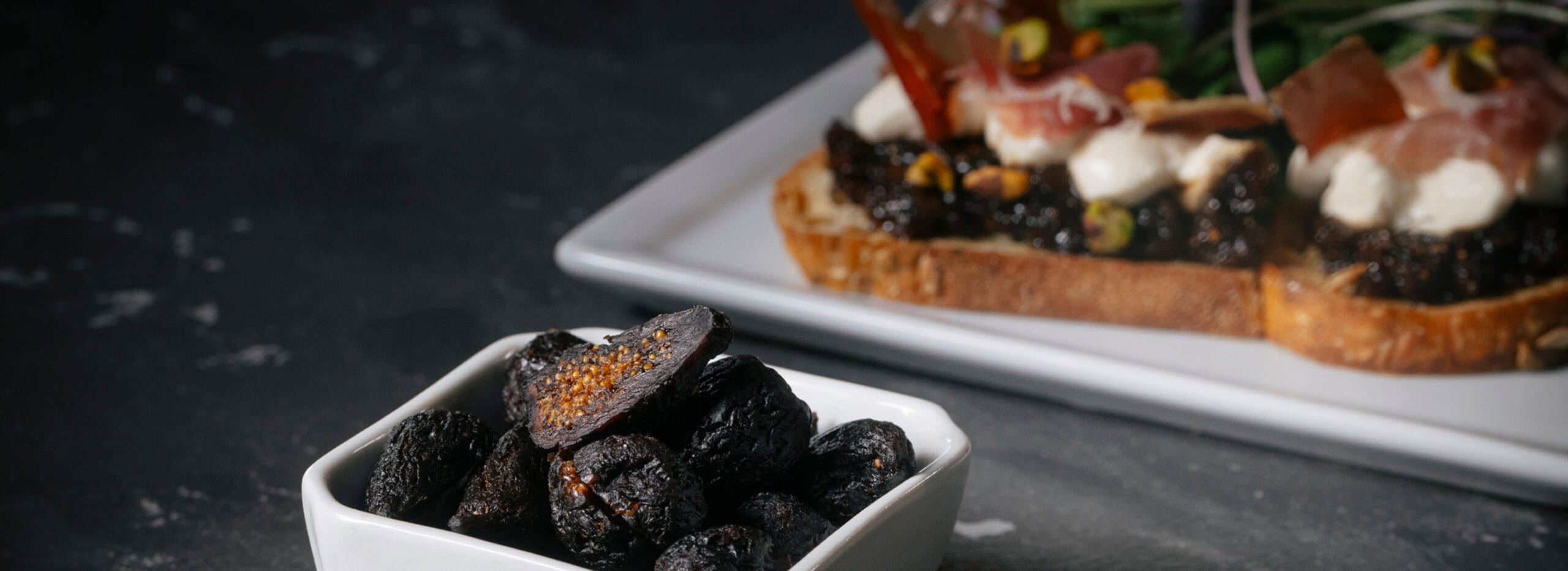 Dried fig slices in front of beautifully made fruit toast.