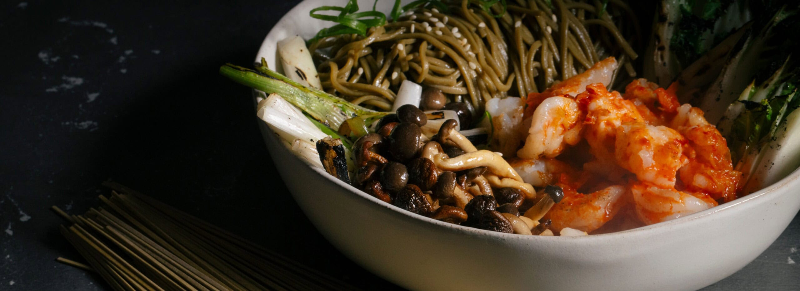 Green spaghetti noodles with delicious gourmet foods in a bowl.