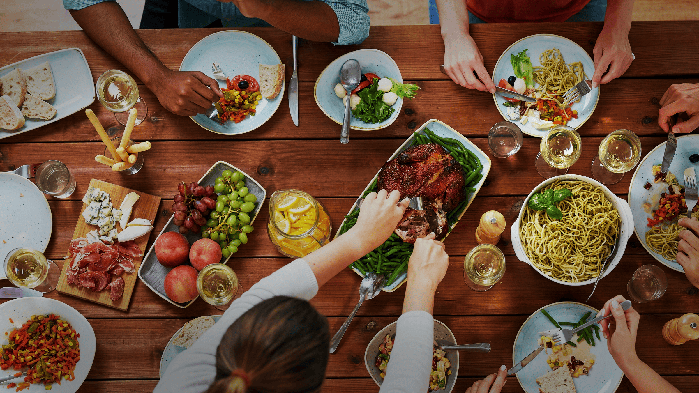 Pasta on a table with people enjoying a lot of delicious foods.