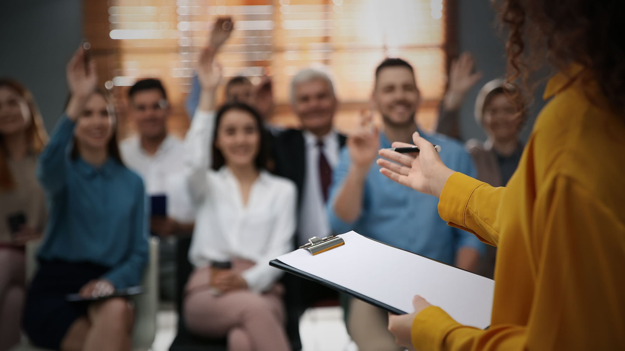 Professionals attending a seminar smiling and raising their hands for people development