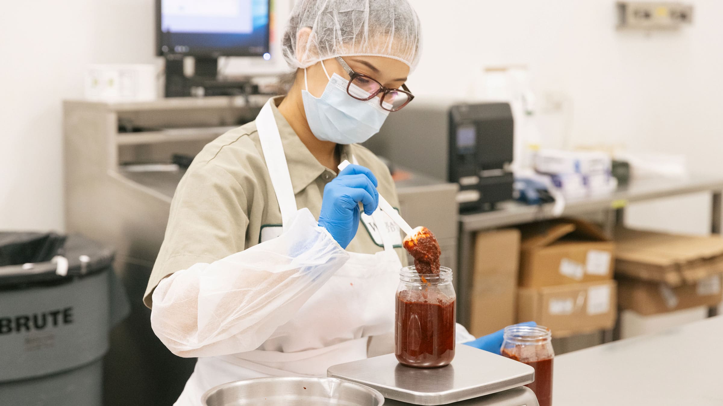 a woodland gourmet employee weighing a jar of spices